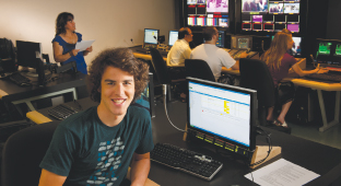 Un étudiant en production télévisuelle travaille à une console dans un studio de télé.